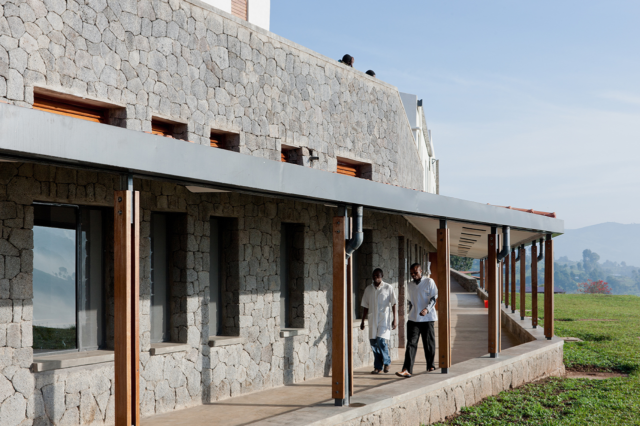 Photo of Butaro District Hospital, Photo by Iwan Baan, Exterior Hallway with Doctor and Patient Passing By