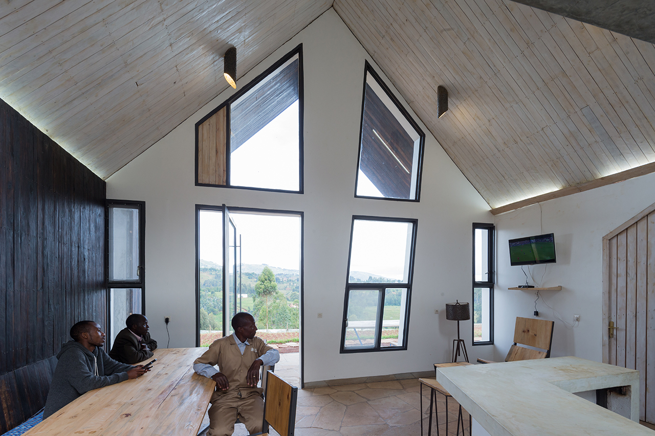 Photo of Butaro Doctors' Sharehousing, Photo by Iwan Baan, an Interior View of a Person adjusting a room's curtains