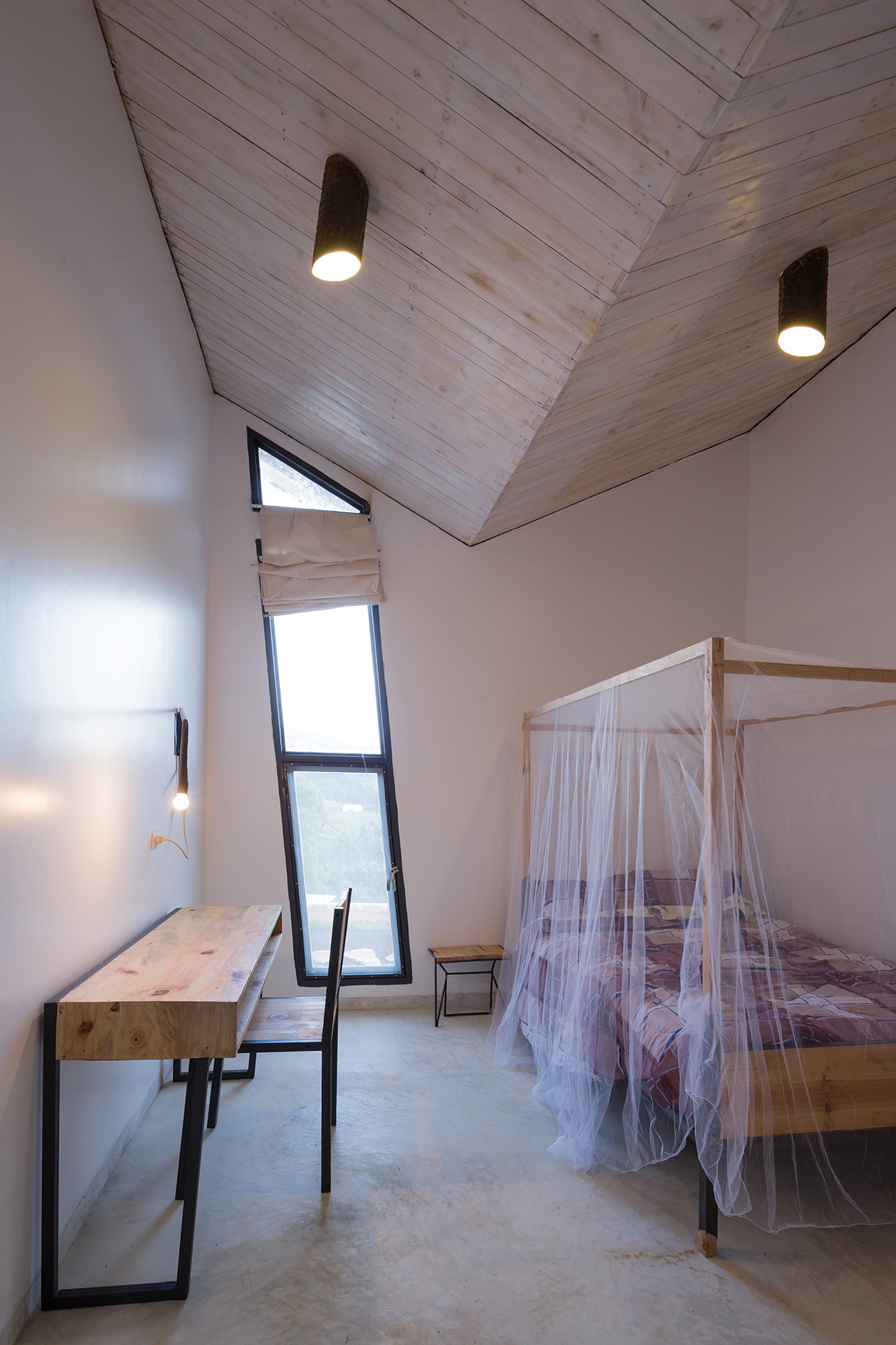 Photo of Butaro Doctors' Sharehousing, Photo by Iwan Baan, an Interior View of a Person adjusting a room's curtains
