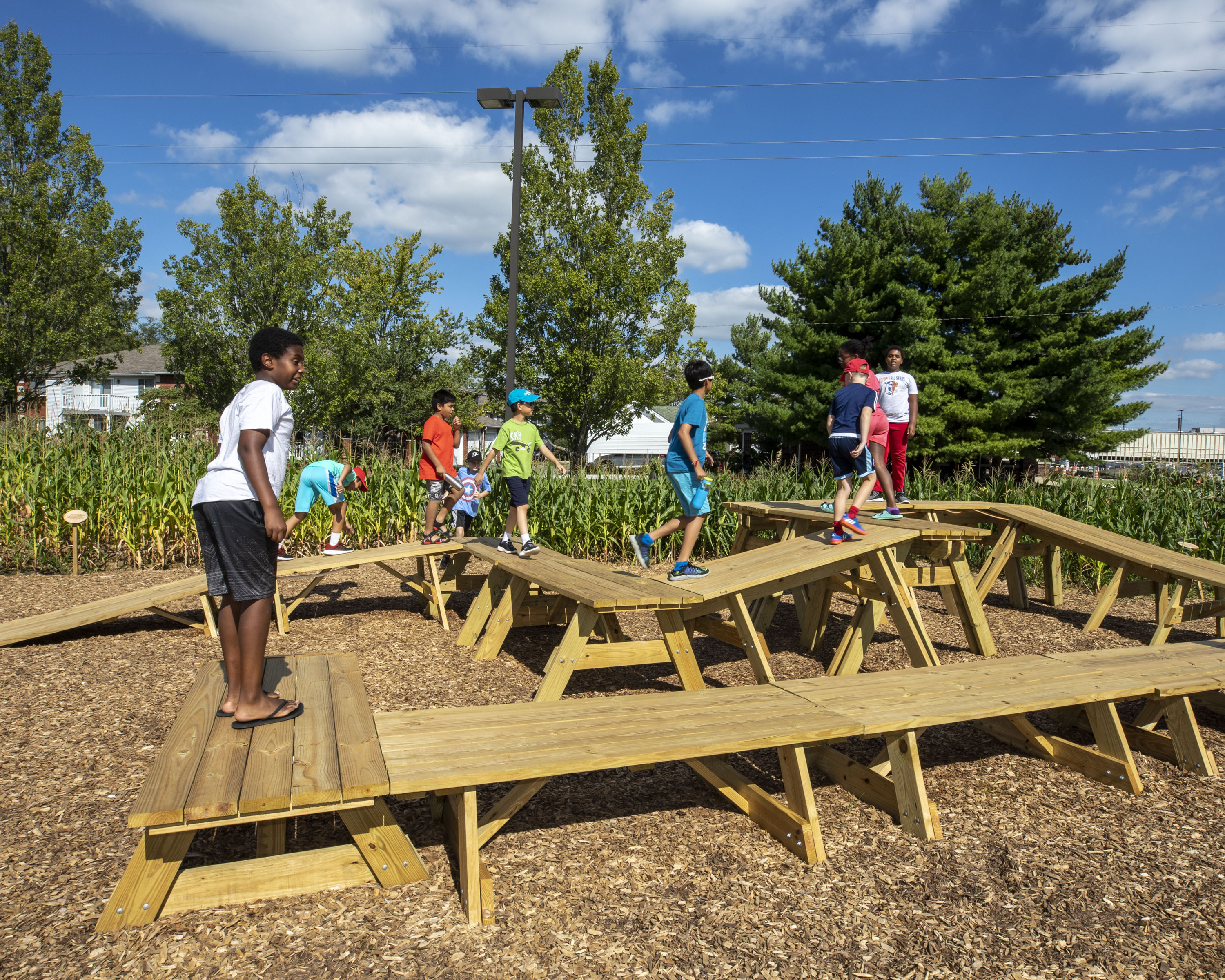 Children from Central Middle School playing on the picnic tables in our Corn / Meal installation